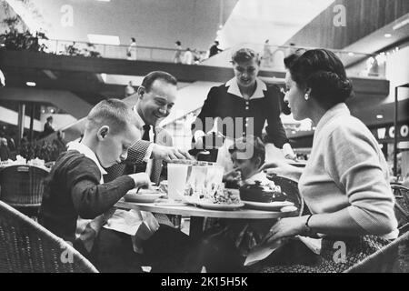 Das Foto ist mit der Bildunterschrift „Minnesota, Southdale (in der Nähe von Minneapolis) Shopping Center“ beschriftbar, das von Victor Gruen entworfen wurde. In einem überdachten Einkaufszentrum können die Käufer bei Winterwetter das „idewalk“-Restaurant nutzen.“ Stockfoto