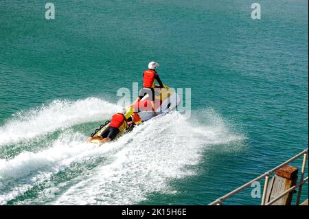 Bournemouth, Dorset, England, Großbritannien, 15.. September 2022, Wetter. Am Nachmittag ist es in der frühen Herbstsonne ruhig. Ein RNLI-Rettungsschwimmer fährt von einem Kollegen auf dem Rücken eines Jetskis. Kredit: Paul Biggins/Alamy Live Nachrichten Stockfoto