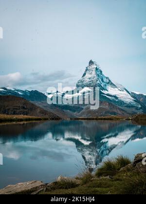 The snowy peak of the Matterhorn in Switzerland is reflected in the surface of a mountain lake. Stockfoto