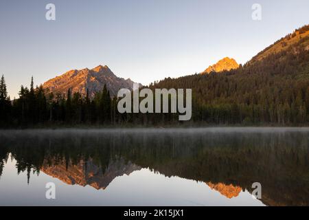 Mount St. John und die Teton Mountains, die sich bei Sonnenaufgang über dem Bearpaw Lake erheben. Grand Teton National Park, Wyoming Stockfoto