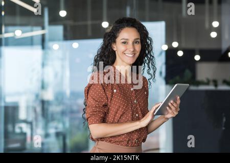 Junge und erfolgreiche Programmiererin, Portrait einer Ingenieurin mit einem Startup-Mitarbeiter im Bürogebäude, der Tablet zum Testen von Anwendungen verwendet und dabei lächelnd auf die Kamera blickt. Stockfoto