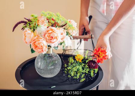 Florist macht Strauß von Rosen Zinnia Amaranth Blumen in Vase auf dem Tisch. Verfahren der Anordnung mit Korb und Hochentaster. Inneneinrichtung Stockfoto