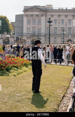 Polizeibeamter, der vor dem Buckingham Palace steht und die Öffentlichkeit und den Palast wenige Tage nach dem Tod von Königin Elizabeth II. Schützt Stockfoto