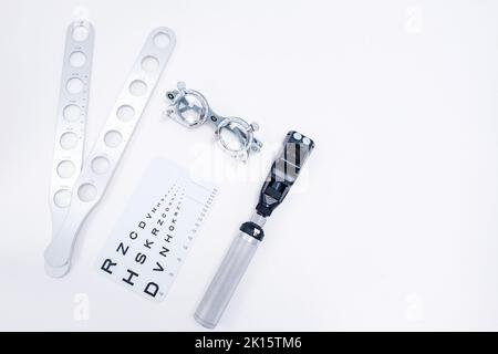 Von oben des Retinoskop-Testchart optischer Rücklinsenrahmen und Retinoskopie-Paddles zur Untersuchung des Sehvermögens auf weißem Hintergrund im Studio angeordnet Stockfoto