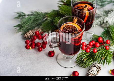 Glühwein mit Gewürzen mit Feiertagsdeko auf weißem Beton-Hintergrund Stockfoto