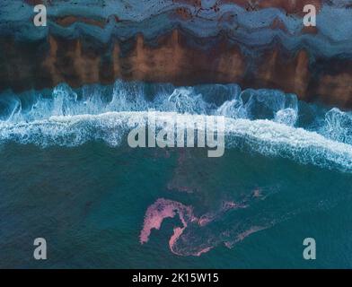 Von oben Dronen Blick auf schäumende Wellen des blauen Meeres plätschern in der Nähe der nassen Küste in stürmischen Abend Stockfoto