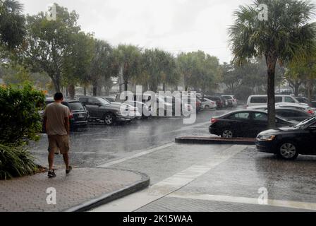 Mann in Shorts überquert den Hotelparkplatz bei starkem Regen, Miami, Florida, USA Stockfoto