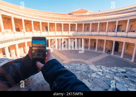 Nicht erkennbare weibliche Touristin, die während eines Besuchs in Granada, Spanien, auf dem Balkon des Palastes von Karl V. fotografiert Stockfoto