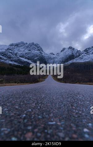 Malerische Aussicht auf leere Bergstraße im Winter unter bewölktem Himmel in Norwegen Stockfoto