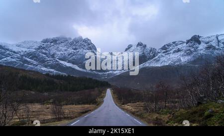 Malerische Aussicht auf leere Bergstraße im Winter unter bewölktem Himmel in Norwegen Stockfoto