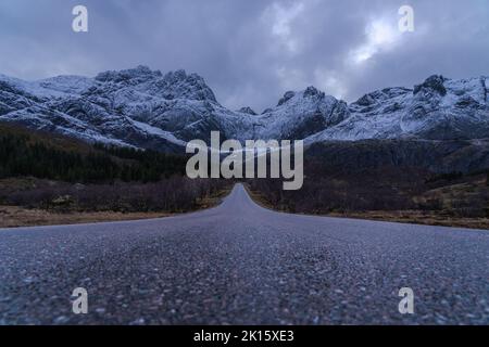 Malerische Aussicht auf leere Bergstraße im Winter unter bewölktem Himmel in Norwegen Stockfoto