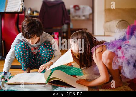 Kleines Mädchen in Kostüm Bugs Bruder, während er ein Buch liest Stockfoto