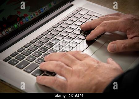 Eine männliche Hand / Finger tippen auf einem Computer Laptop-Tastatur, Apfel macbook Laptop Stockfoto