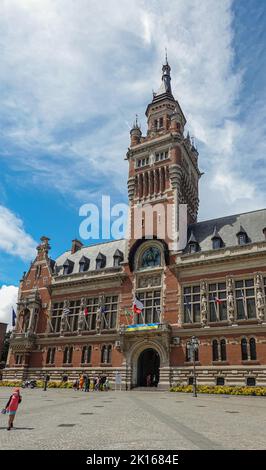 Europa, Frankreich, Dunkerque - 9. Juli 2022: Menschen auf dem Platz Charles Valentin vor dem Glockenturm des historischen Rathauses unter blauer Wolkenlandschaft. Alarmmeldung Stockfoto