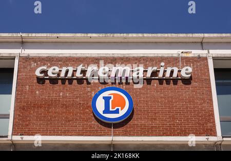 Europa, Frankreich, Dunkerque - 9. Juli 2022: Nahaufnahme des Namensschildes auf der roten Ziegelmauer des Center Marine Einkaufszentrums unter blauem Himmel Stockfoto