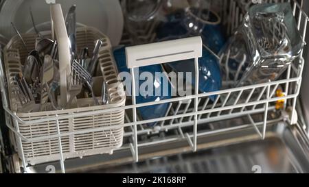 Geschirrspüler mit sauberem Geschirr.Geräte für die Küche. Teller, Gabeln und Gläser in der Spülmaschine. Stockfoto