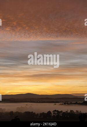 Wunderschöner Sonnenaufgang mit abstrakter, mehrfarbiger, dramatischer Wolkenlandschaft über den Yarra Ranges in Victoria, Australien Stockfoto