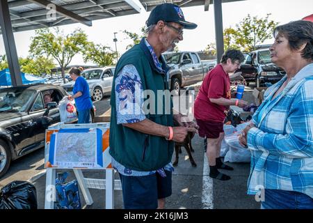 Rocklin, Kalifornien, USA. 15. September 2022. Derek Jones, links, die aus dem Forrest Hill Mobile Home Park evakuiert wurde, erzählte Lynda Hogge, rechts, die sagt, sie habe vier Hausbrände überlebt, Listen mit Dingen, die Evakuierte brauchen, nachdem sie am Donnerstag, den 15. September 2022, Taschen mit Kleidung zum Parkplatz B am Sierra College in Rocklin gebracht hatte. Obwohl selbst ein Evakuierte war, hat Jones anderen Mosquito Fire Evakuierten geholfen und auf einer Matratze auf der Baustelle geschlafen. „Das Gefühl von Verlust ist unvorstellbar und mein Herz geht an all diese Menschen“, sagte Hogge. Links ist eine Karte des Brandbereichs zu sehen. (Bild: © Renée C. Stockfoto