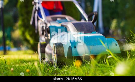 Rasenmäher auf grünem Gras im modernen Garten oder Hinterhof. Maschine zum Schneiden von Rasen. Werkzeuge und Geräte für die Gartenpflege Stockfoto