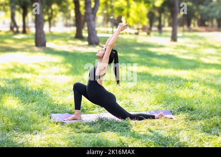 Junge Schwangere praktiziert Yoga dabei Ashwa sanchalanasana Übung, Reiter Pose, tun Körper Stärkung im Park an einem sonnigen Sommermorgen o Stockfoto