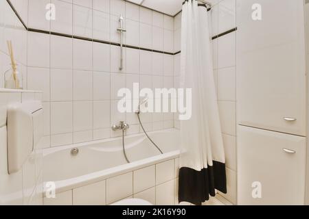 Waschbecken mit Spiegeln und sauberer Badewanne im modernen Badezimmer mit weiß gefliesten Wänden Stockfoto