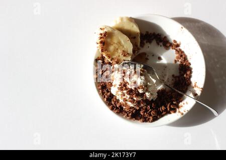 Teller mit Hüttenkäse mit hausgemachtem Müsli, Zimt, Honig und Banane. Gesundes Frühstücksnahrung Konzept. Stockfoto