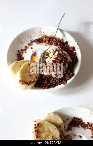 Frühstücksteller mit Hüttenkäse mit Müsli, Honig und Banane. Gesundes Dessert-Food-Konzept. Stockfoto