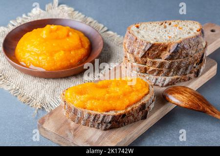 Sandwich mit leckerer Kürbismarmelade auf grauem Tisch Stockfoto