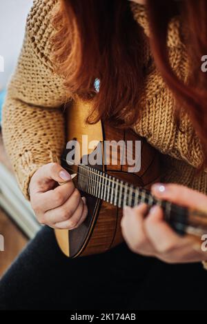 Domra Folk Musikinstrument in weibischer Hand. Weibliche Hände mit 4 Saiten Naturholz Handgefertigtes Musikinstrument Domra Close Up Stockfoto