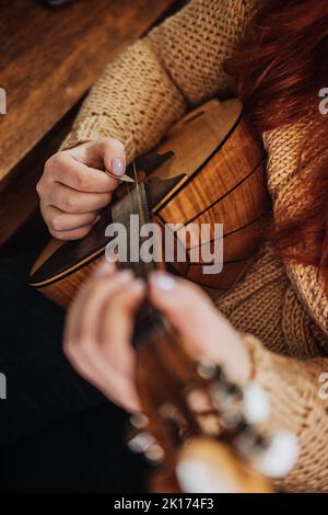 Domra Folk Musikinstrument in weibischer Hand. Weibliche Hände mit 4 Saiten Naturholz Handgefertigtes Musikinstrument Domra Close Up Stockfoto