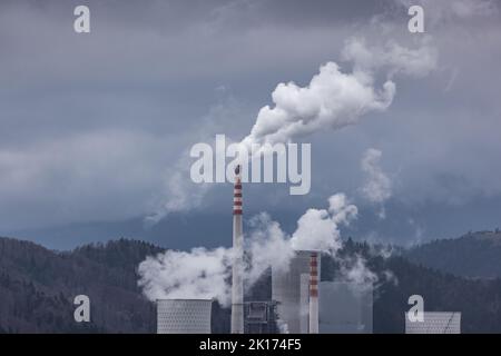 Luftverschmutzung durch ein thermisches Kraftwerk. Dicker Rauch, der aus einem Kamin und einem Turm in die Atmosphäre aufwabt Stockfoto