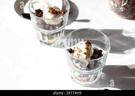 Desserts. Vanilla Ice Cream serviert mit hausgemachtem Müsli. Zwei Gläser mit Eiscreme auf weißem Hintergrund. Stockfoto