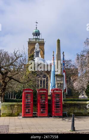 Northampton Town Centre View mit drei roten Telefonzellen vor einem Lutyens entworfen, Kriegerdenkmal, Allerheiligen Kirche im Hintergrund. Stockfoto