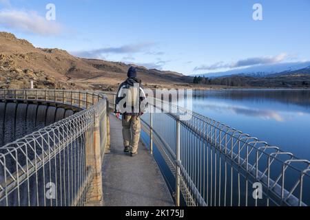 Mann, der auf der Butchers Dam Loop Track läuft. Wasser fällt über verschüttete Wasser. Alexandra, Central Otago. Stockfoto