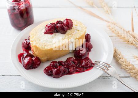 Sahnetorte mit Kirschkompott auf einem Teller auf weißem Hintergrund Stockfoto