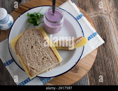 Käsesandwich mit Sauerteigbrot und altem gouda. Serviert mit einem Joghurt zum Frühstück auf einem Teller Stockfoto