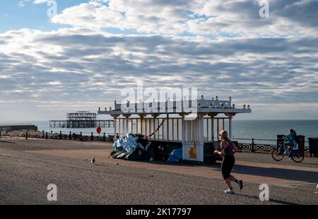 Brighton UK 16. September 2022 - Ein Läufer kommt an einem Tierheim vorbei, in dem an der Küste von Brighton ein Obdachlosenlager errichtet wurde, an einem sonnigen, aber kühlen Tag, da die Temperaturen in den nächsten Tagen in Großbritannien voraussichtlich sinken werden: Credit Simon Dack / Alamy Live News Stockfoto