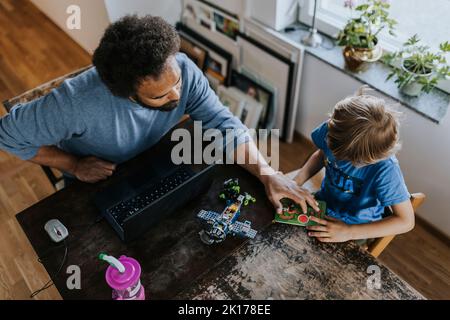 Vater arbeitet von zu Hause aus und spielt mit dem Sohn Stockfoto