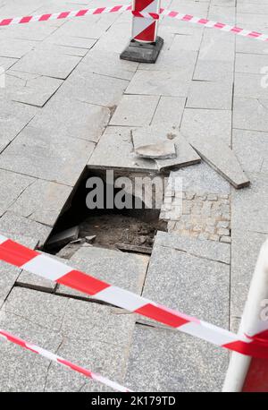 Schlagloch im Bürgersteig mit Klebeband gesichert Stockfoto