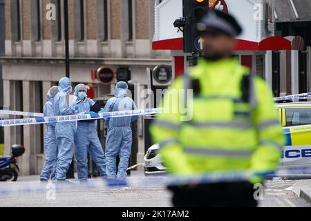 Forensische Beamte und Polizisten am Tatort in der Shaftesbury Avenue im Zentrum von London, wo zwei männliche Polizisten um 6am von einem Mann erstochen wurden. Beide Offiziere werden derzeit von Sanitätern behandelt. Der Verdächtige wurde wegen des Verdachts verhaftet, schwere körperliche Schäden verursacht und einen Nothelfer angegriffen zu haben. Bilddatum: Freitag, 16. September 2022. Stockfoto