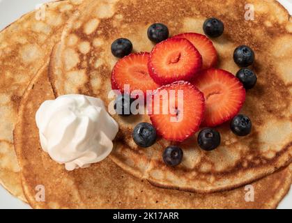 Pfannkuchen mit Erdbeeren, Blaubeeren und Rahm Stockfoto