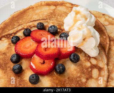 Pfannkuchen mit Erdbeeren, Blaubeeren, Rahm und Ahornsirup Stockfoto