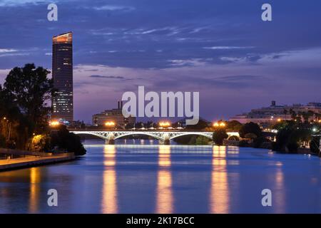 Blick auf den Guadalquivir-Fluss in Sevilla von der Brücke bei Sonnenuntergang. Stockfoto