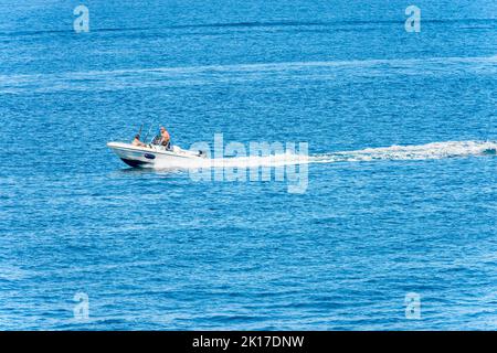 Weißes Schnellboot mit zwei erwachsenen Fischern an Bord mit Angelruten, in Bewegung im Mittelmeer, Golf von La Spezia, Ligurien, Italien, Europa. Stockfoto