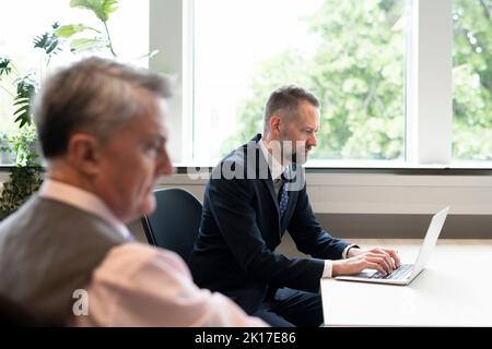 Geschäftsmann mit Laptop im Büro Stockfoto