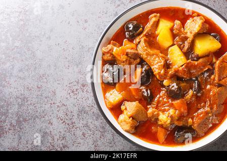 Würziger Lammeintopf mit Pflaumen, Tomaten, Kartoffeln und Safran aus nächster Nähe auf einem Teller auf dem Tisch. Iranisches Essen. Horizontale Draufsicht von oben Stockfoto