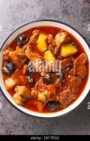 Persian Plum Eintopf Khoresht Aloo mit Lamm aus der Nähe in der Schüssel auf dem Tisch. Vertikale Draufsicht von oben Stockfoto