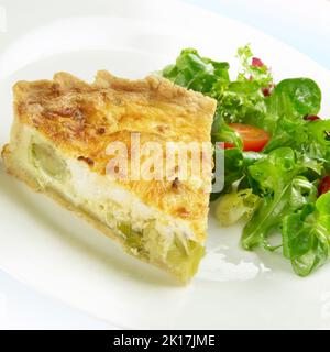 Scheibe Quiche aus Lauch- und Ziegenkäse, auf einem Teller mit Blattsalat Stockfoto