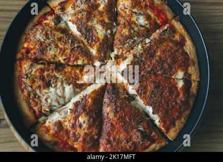 Leckere Thunfisch-Pizza mit Sardellen und grünem Pfeffer. Köstliches traditionelles Fast Food auf Holzbretttisch. Draufsicht. Stockfoto