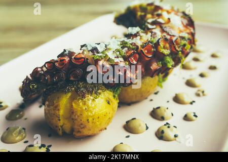 Leckere gegrillte galicische Krake Bein mit gerösteten Kartoffeln und Knoblauch Aioli auf Holztisch Stockfoto